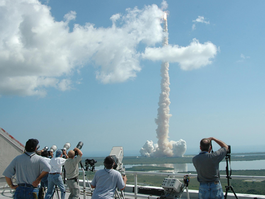 Spectators at the NASA News Center at Kennedy Space Center view the lanch.